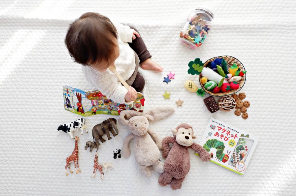 おもちゃや絵本に囲まれて座る男の子の画像